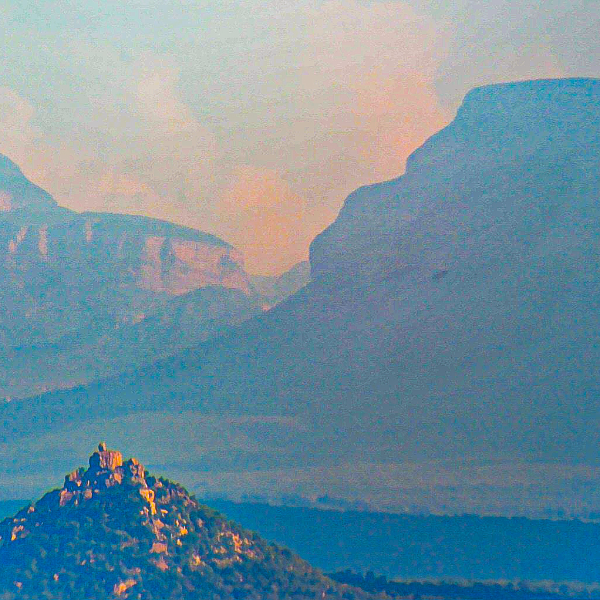 Layered blue ridges and a lit rock peak in evening haze