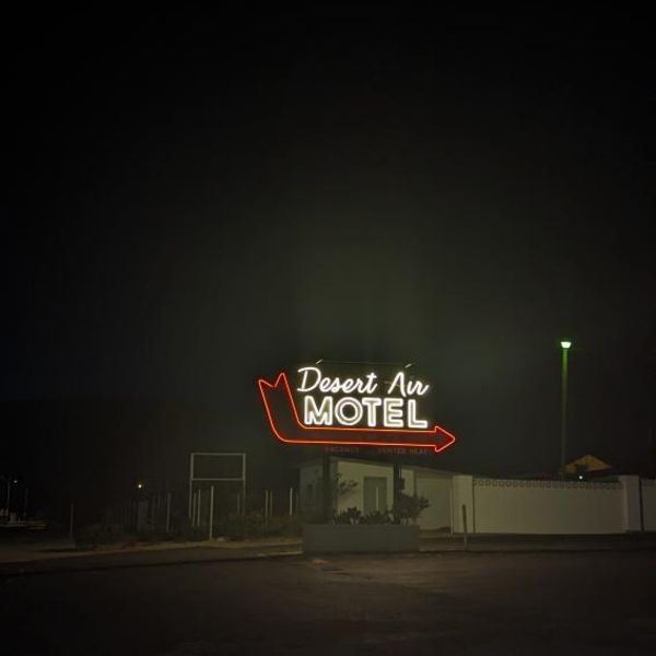 Neon Desert Air Motel sign burning against a black desert night