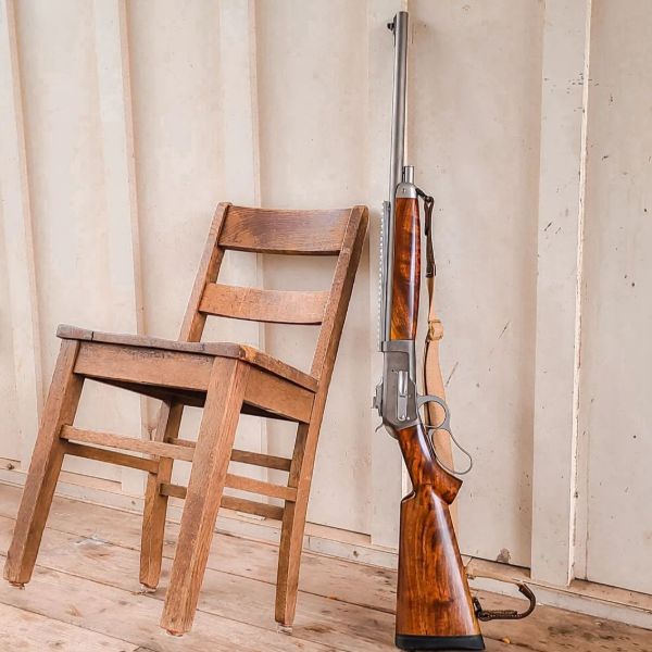 Muzzleloader firing in period hunting dress, smoke hanging in bare winter timber