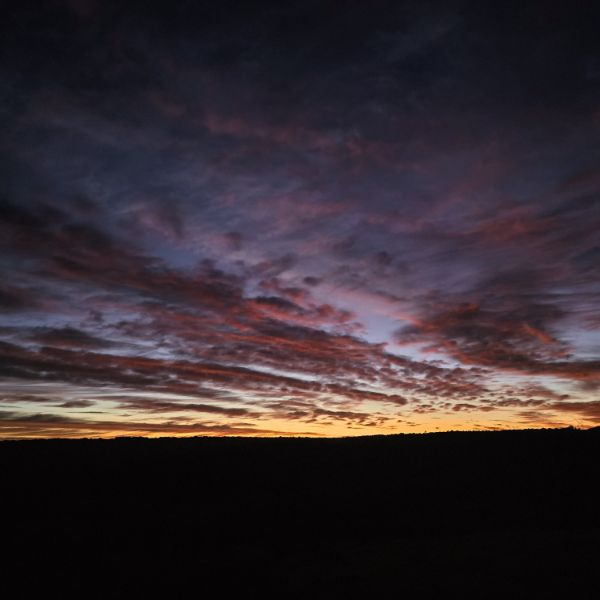 Red and violet dawn cloud over a dark ridgeline
