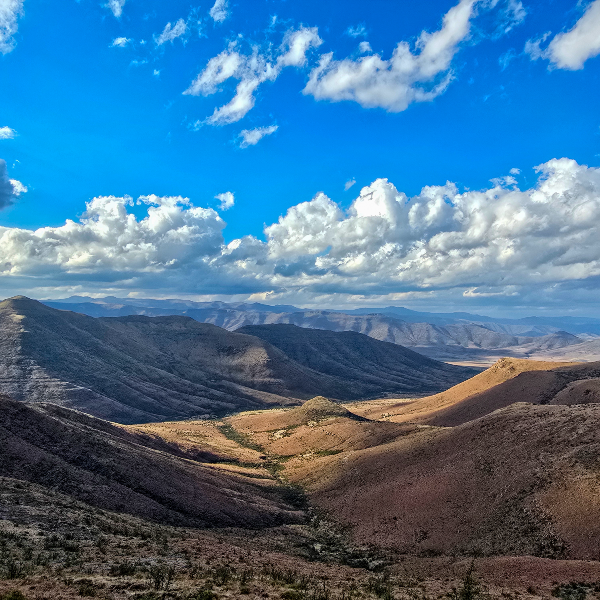 Deep valley between arid mountain ranges under towering cumulus