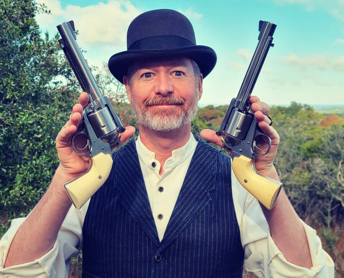 Jon Wayne Taylor holding a single-action revolver in each hand